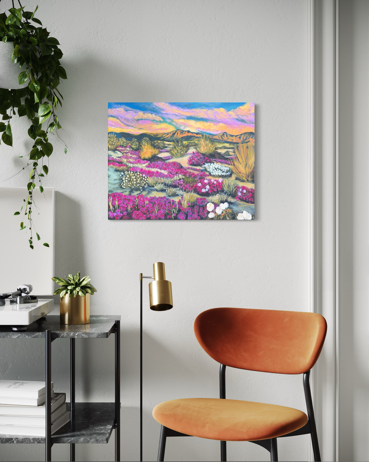 Colorful flower desert landscape painting on a wall above a modern chair and side table.