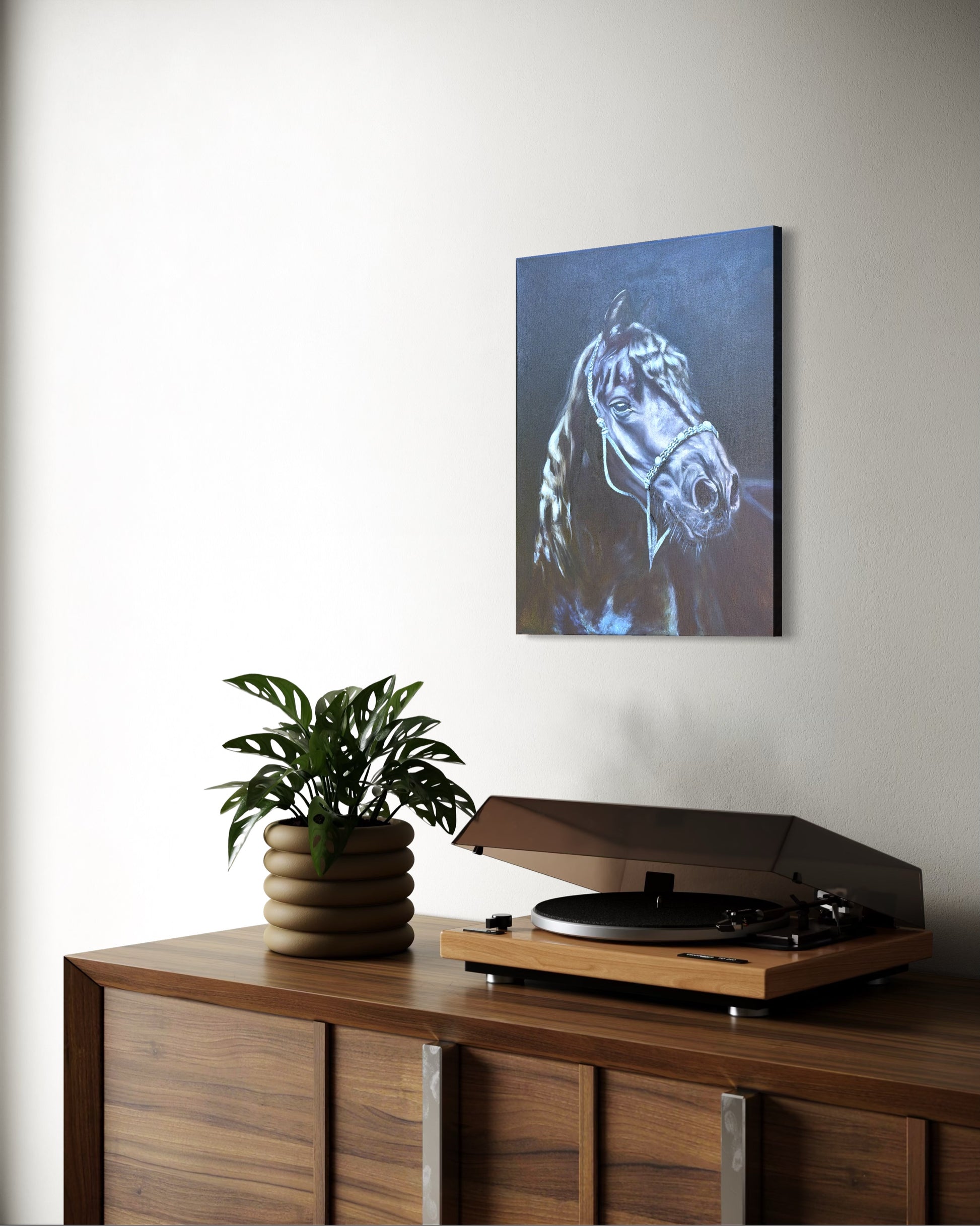 Wooden cabinet with a plant and turntable, wall art oil painting of a black horse's head above.