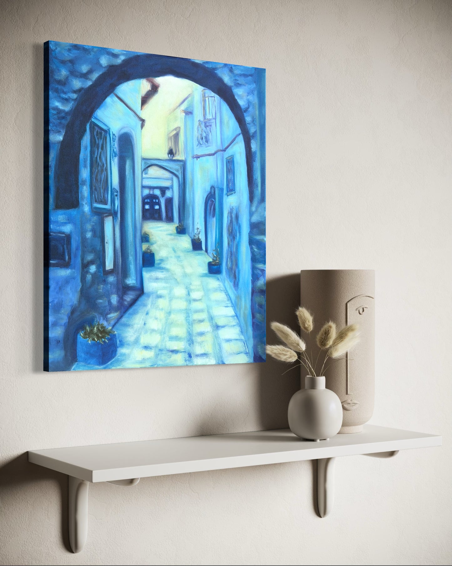 Oil painting of a blue alleyway hanging on a wall above a white shelf with decorative items.