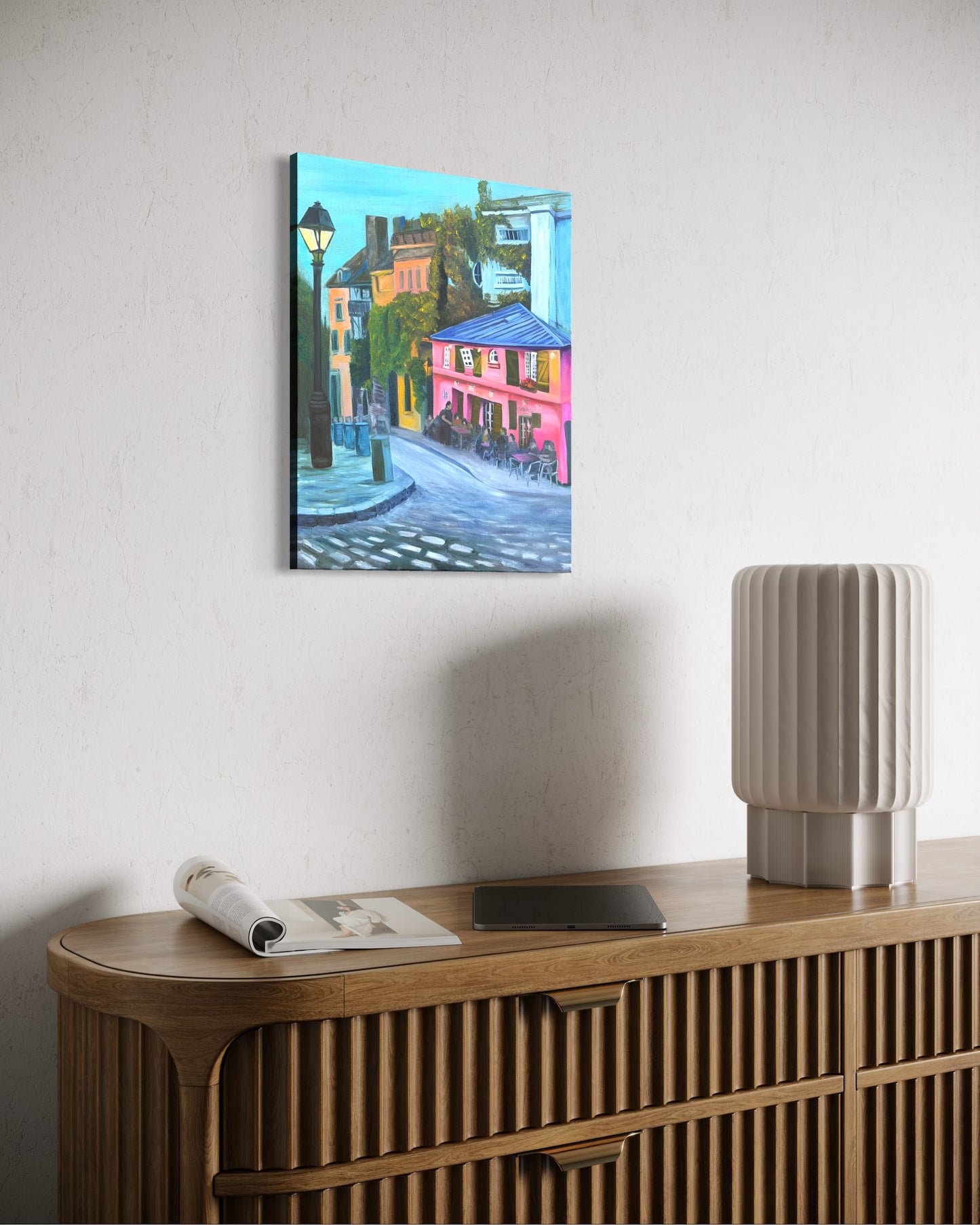Colorful oil painting of a street scene on a wall above a wooden console table.