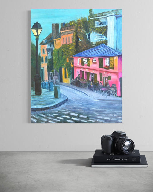 Colorful oil painting of a street scene with a pink cafe hanging on a wall with a camera below.