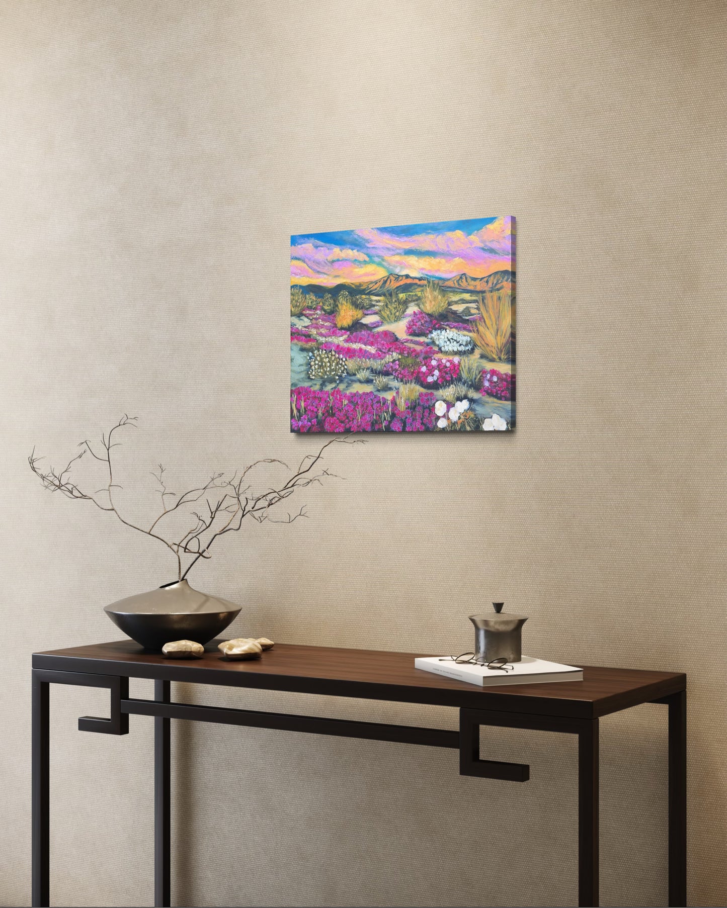 Colorful flowering desert landscape oil painting on a wall above a wooden console table with decorative items.
