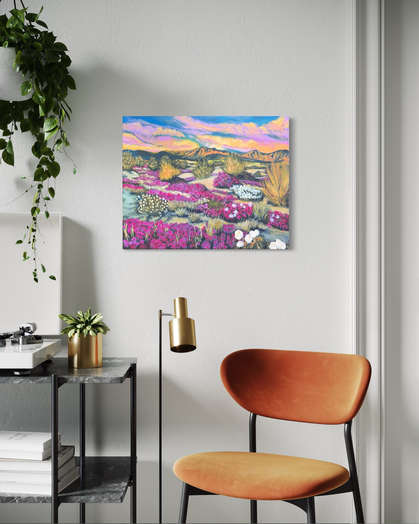 Colorful flower desert landscape painting on a wall above a modern chair and side table.