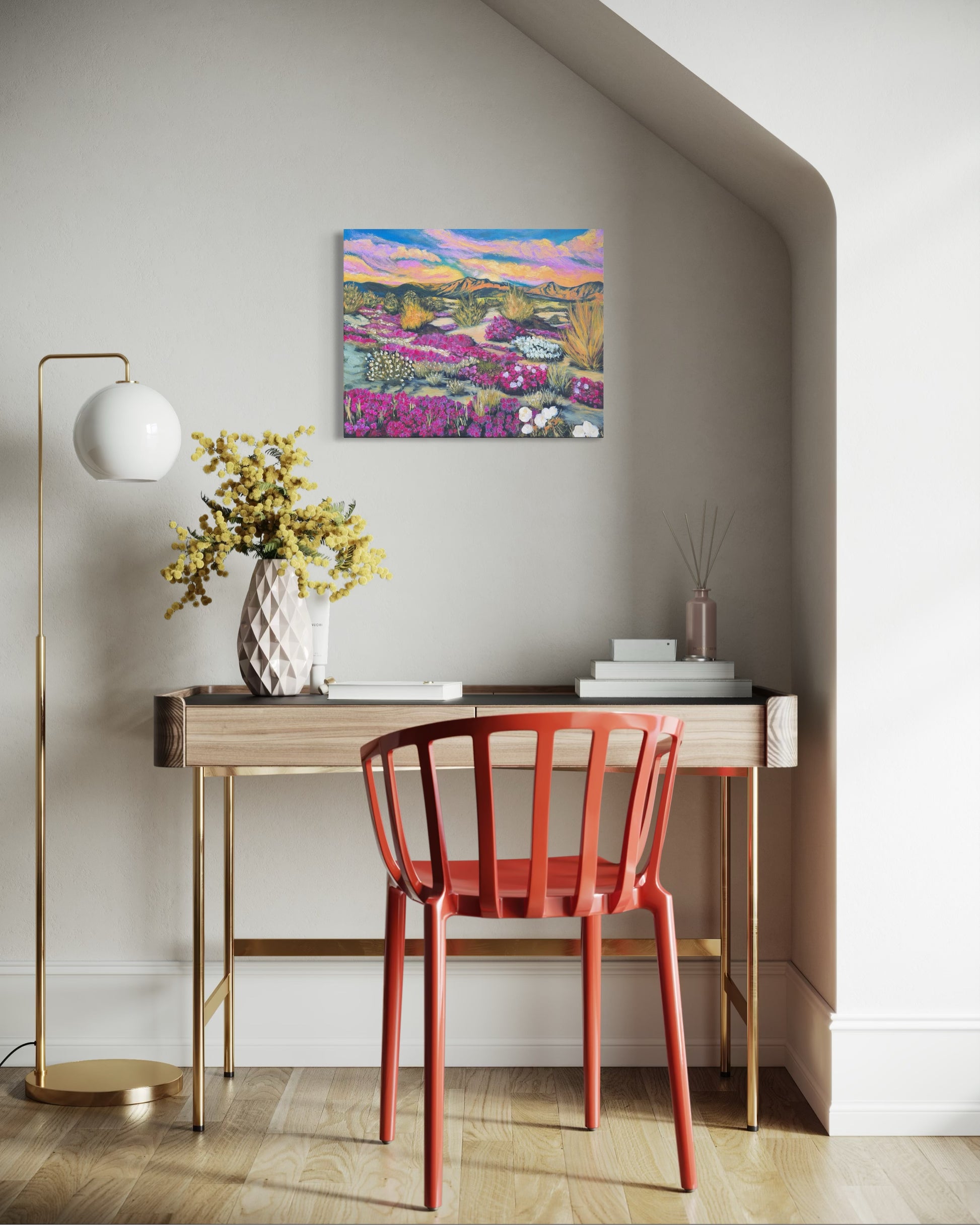 Modern interior with a red chair, wooden desk, and colorful flowering desert landscape painting on the wall.
