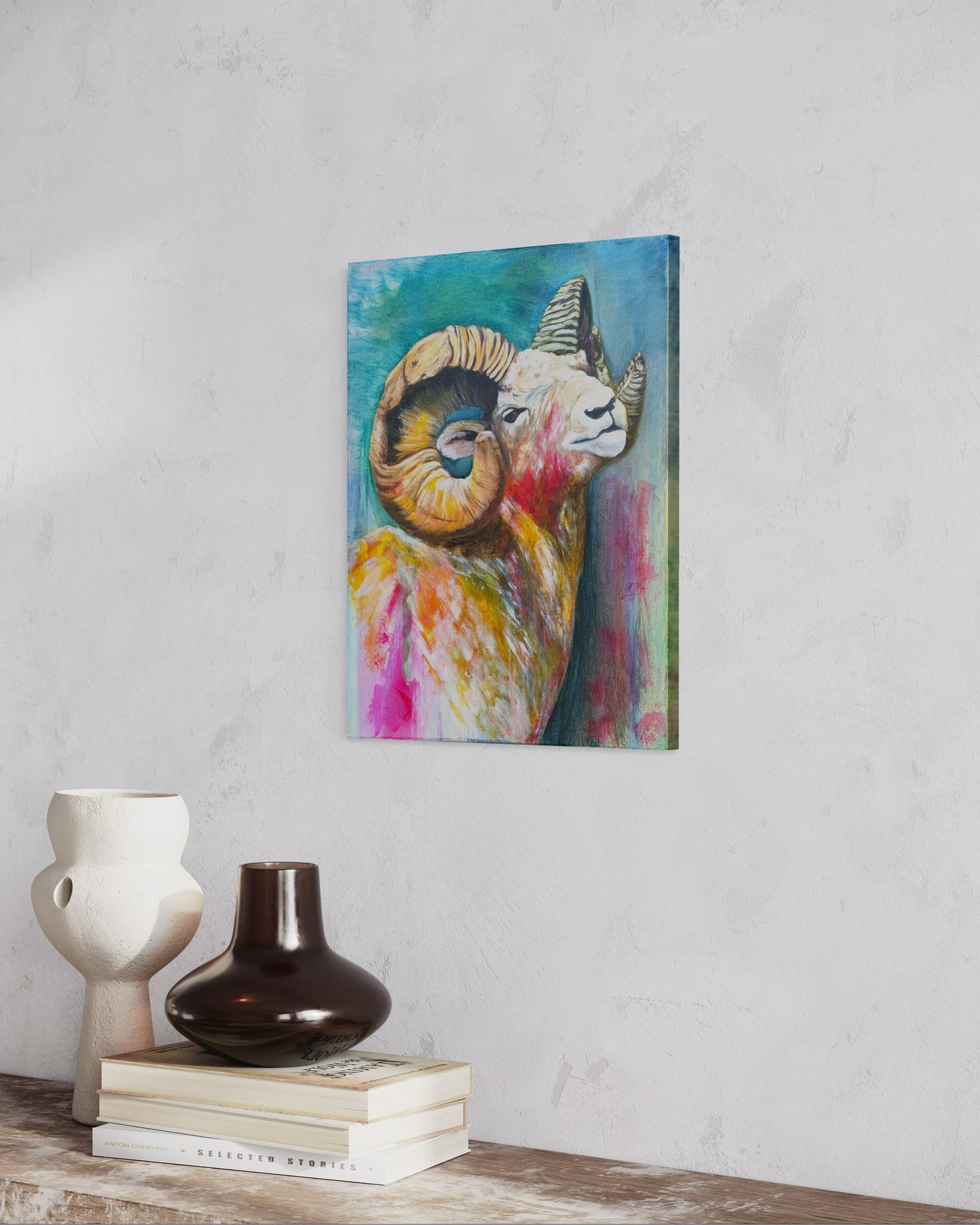 Colorful oil painting of a ram with spiral horns hanging on a wall above books and vases.